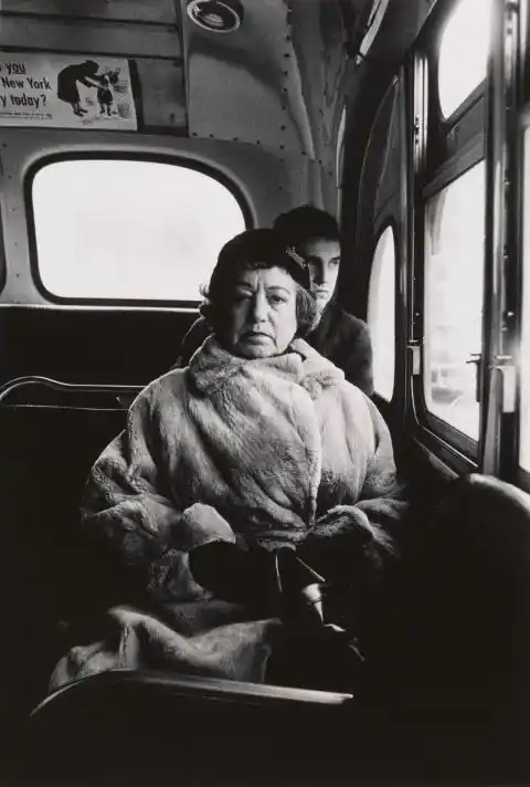 Fotografía en blanco y negro de una mujer con abrigo sentada junto a la ventana de un autobús